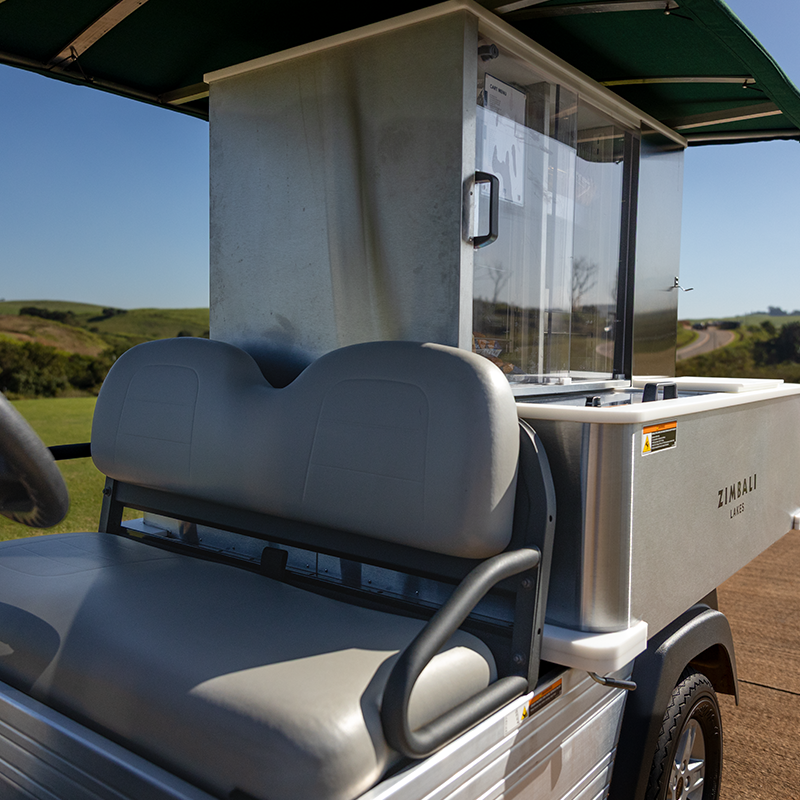 A close-up of the Club Car Café Express, fully stocked with refreshments and snacks, ready to serve golfers at the Zimbali Lakes Ernie Else Signature golf course. It also shows the two front seats.