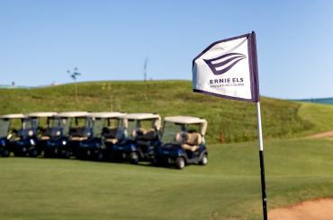 The Zimbali Lakes Ernie Els Signature golf course with the Ernie Els Signature Course flagstick in the foreground and in the background is a fleet of Club Car golf carts.