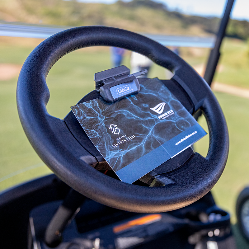 A steering wheel of the Club Car Tempo 2 at the Zimbali Lakes golf course with a booklet clipped to the wheel with a pencil.