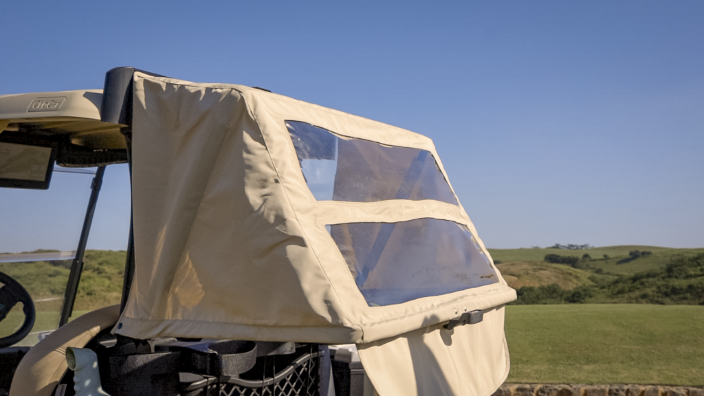 A Club Car Bag Protector on a blue Club Car Tempo that is open to shield the clubs from the sun. The transparent panels are visible.