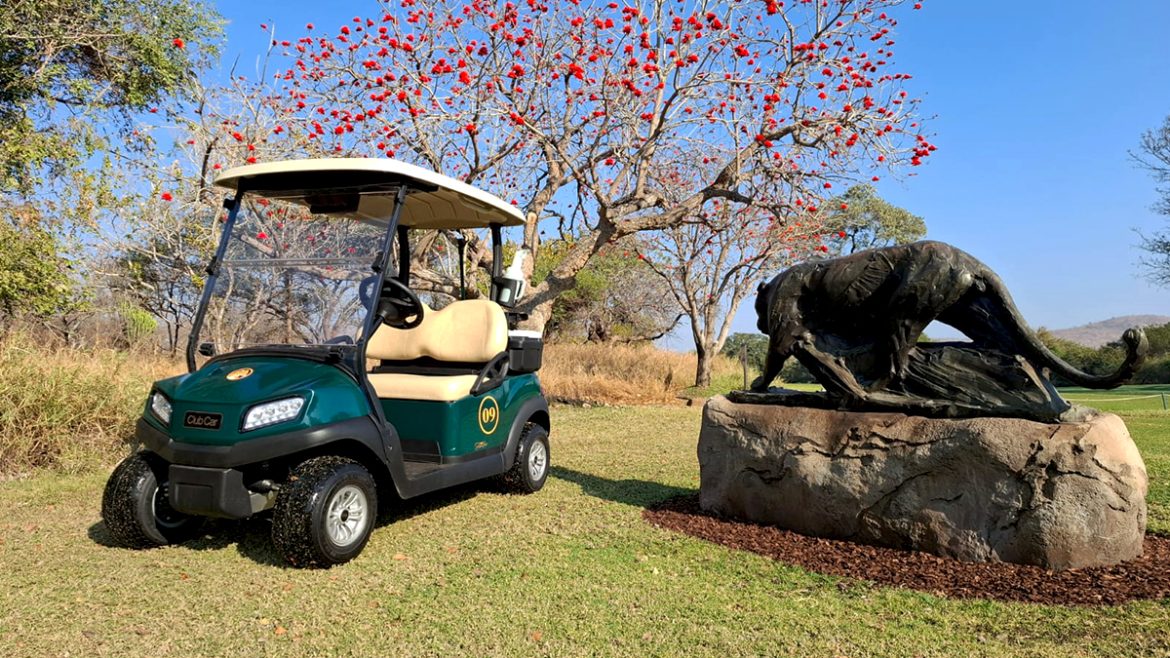 A photo of a Club Car Tempo next to one of the iconic statues at Leopard Creek