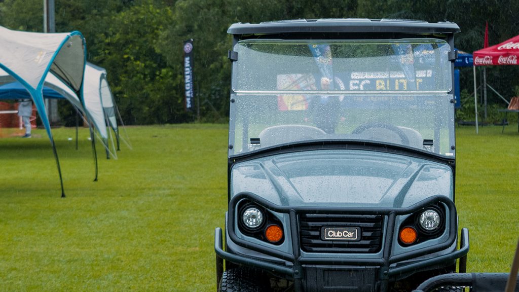 A photo of a Club Car Tempo taken in the rain.  It has a windshield which is covered by rain drops.